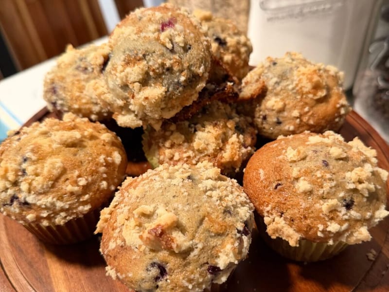 blueberry muffins with oat streusel topping piled on a wooden board